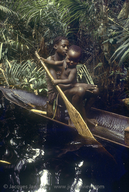 Africa, Democratic Republic of the Congo, Ngiri River islands area, Libinza tribe, girl with baby learning how to paddle in canoe in swamp forest.